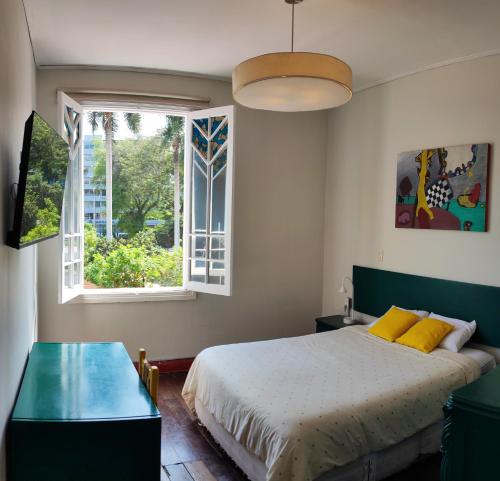 Un dormitorio con una cama con almohadas amarillas y una ventana en Flying Dog Hostel, en Lima