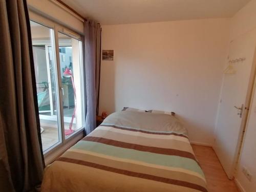 a bed in a room with a large window at Appartement de charme, Garage, Terrasse, Piscine in Lyon