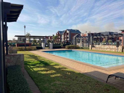 a swimming pool in the middle of a yard at Luxury 1bed Serengeti OliveWood ORT Airport in Kempton Park