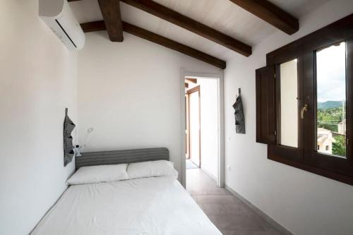 una camera bianca con un letto e una finestra di Casa tipica nel borgo antico ad Armungia