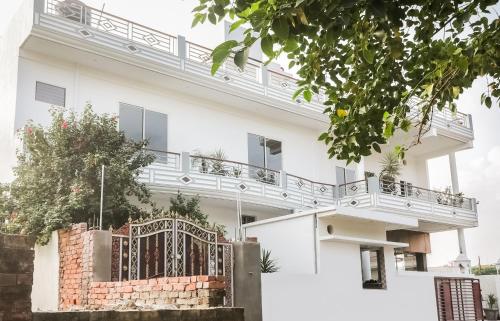uma casa branca com uma varanda em cima em Capital O 61009 Hotel Raj Mahal Sarnath em Varanasi