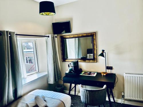 a bedroom with a desk and a mirror and a bed at Hotel No5, Beachfront with Free Private Car Park in Llandudno