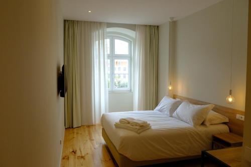 a bedroom with a bed with white sheets and a window at Liberator Rossio in Lisbon
