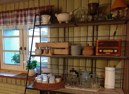 a kitchen with shelves filled with dishes and a microwave at Mošķu Pirts meža māja in Turaida