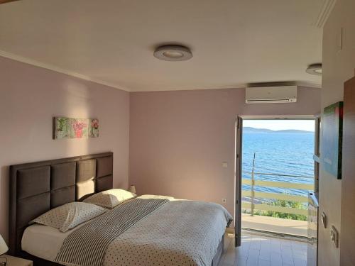 a bedroom with a bed and a view of the ocean at Apartments Children's paradise in Sukošan