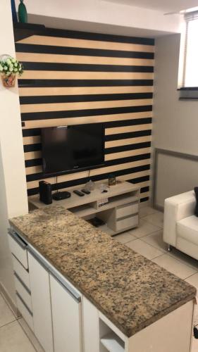 a living room with a television and a counter top at FlatsRose CH Flamboyant Conforto e qualidade in Goiânia