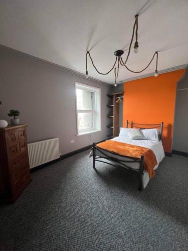 a bedroom with a bed with an orange wall at Stylish 5 bedroom /7bed apartment in Seacombe