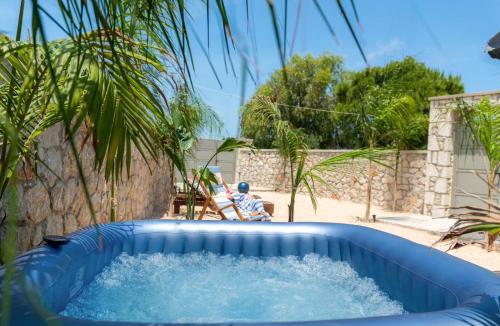 a blue plunge pool in a yard with a palm tree at Odyssea Sea View Apartment one minute from the sea in Kremasti