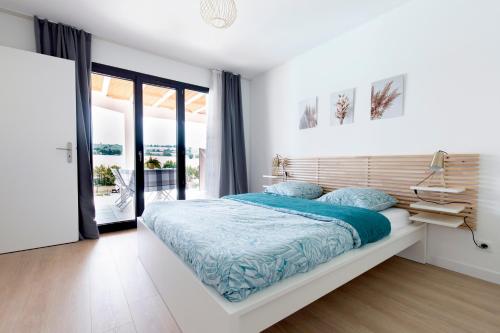 Les Coteaux de Toulouse في Aureville: غرفة نوم بيضاء مع سرير وشرفة