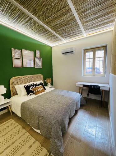 um quarto com uma parede verde, uma cama e uma secretária. em casa Albufera junior em Valência