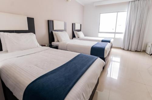 a hotel room with two beds and a window at Hotel Miraval in Montería