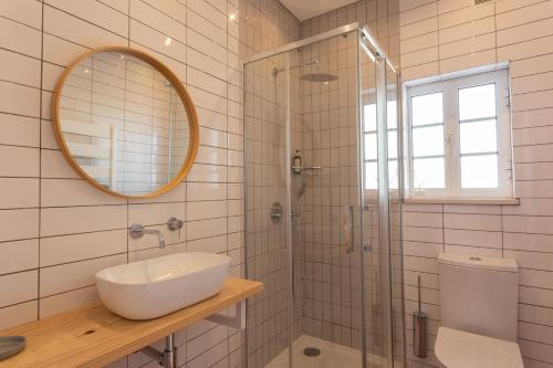 a bathroom with a sink and a shower with a mirror at Casa da praia in Carrapateira