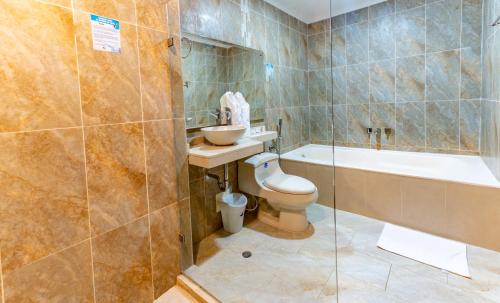 a bathroom with a tub and a toilet and a sink at Hotel Miraval in Montería