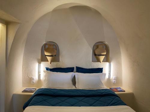 a bedroom with a bed with blue and white pillows at Amphora Villas Oia Santorini in Foinikiá