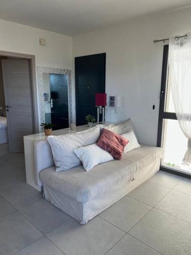 un sofá blanco con 3 almohadas en una habitación en Très joli 2 pièces calme ensoleillé avec piscine en Niza