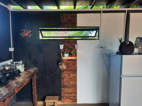 eine Küche mit einem Kühlschrank und ein Fenster in einem Zimmer in der Unterkunft Moehiva Camping Rapa Nui in Hanga Roa