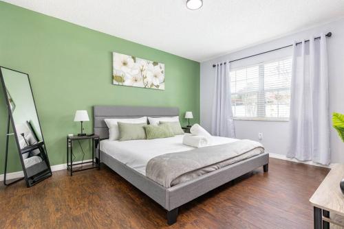 a bedroom with a bed and a green wall at The Villa Verde - Luxury Clearwater by BlueBellaEstate in Largo