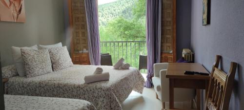 1 dormitorio con cama, escritorio y ventana en Hotel Fuertescusa, en Fuertescusa