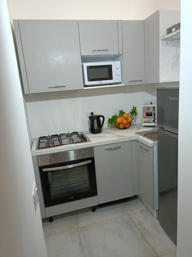 a white kitchen with a stove and a microwave at Clio's House - Mondello in Mondello