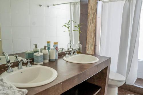 a bathroom with two sinks and a toilet and a mirror at Casa de Playa con Piscina Exclusiva in Pisco