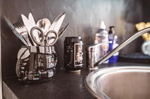 une tasse avec ciseaux sur un comptoir à côté d'un évier dans l'établissement ExploreReims - Studio intergalactique chic proche gare/centre, à Reims