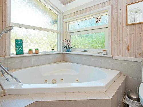 a large white tub in a bathroom with a window at Four-Bedroom Holiday home in Ebeltoft 12 in Ebeltoft