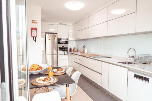 une cuisine avec des placards blancs et une table avec de la nourriture. dans l'établissement Pilgrim Home, à Fátima