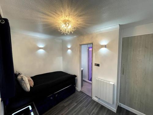 a bedroom with a black bed and a chandelier at Chic 2 Bedroom Flat in Trimley Heath