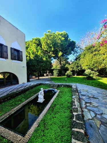 a garden with a fountain in front of a house at Lemuria Manor, Wine Dark Sea Villas in Rhodes Town