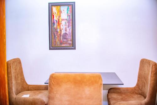 a table with two chairs and a painting on the wall at Homey 2-Bed-Apt 24HRS POWER & Unlimited Internet Access in Lagos