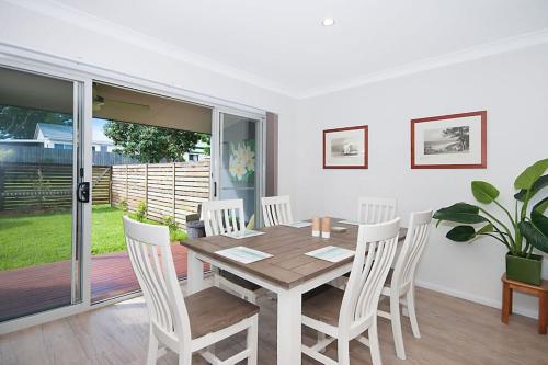 a dining room with a wooden table and white chairs at LUXURY TOWNHOUSE! Walking distance to everything! in Yamba