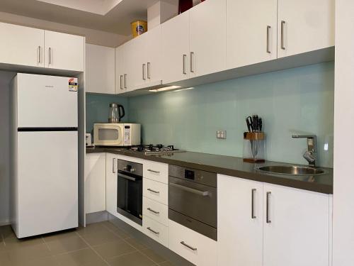 a kitchen with white cabinets and a white refrigerator at Quiet apartment adjacent Parliament House in Kingston 