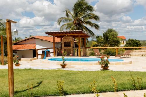 a pool with a gazebo and a palm tree at Apartamentos da Jangada in Canoa Quebrada
