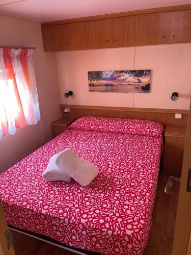 1 dormitorio con cama roja y toalla blanca en Chalet-home familiar "CAL DENVER" "Pet friendly", en Sant Carles de la Ràpita