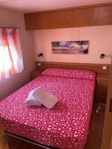 a bedroom with a red bed with a white towel on it at Chalet-home familiar "CAL DENVER" "Pet friendly" in Sant Carles de la Ràpita