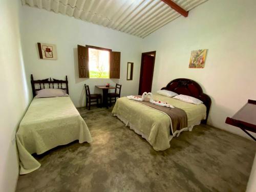 1 dormitorio con 2 camas y mesa. en Pousada Serra do Camulengo, en Barra da Estiva