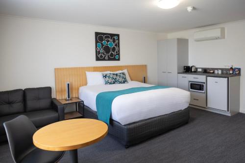 a hotel room with a bed and a table and a couch at Bairnsdale International in Bairnsdale