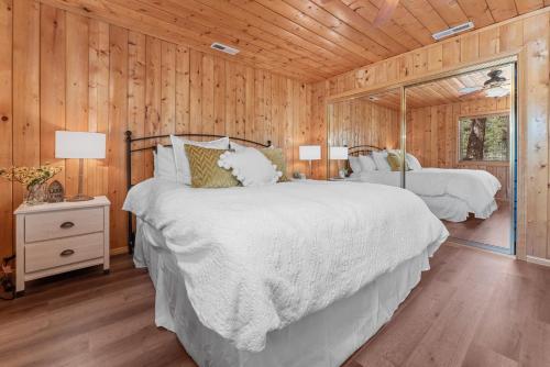 Un dormitorio con dos camas y una pared de madera. en Serenity Knoll - Comfortable, spacious single-level cabin! Newly remodeled! Hot Tub and Pool Table!, en Big Bear Lake