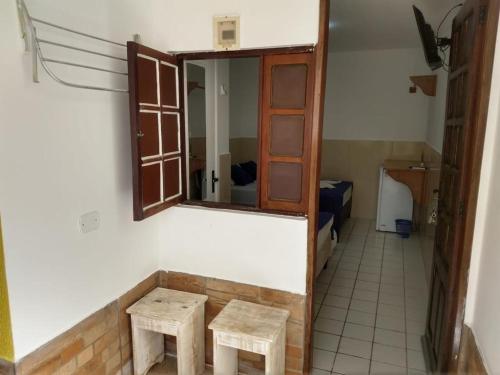 Habitación con espejo y 2 taburetes de madera en Pousada Farol do Porto en Porto De Galinhas
