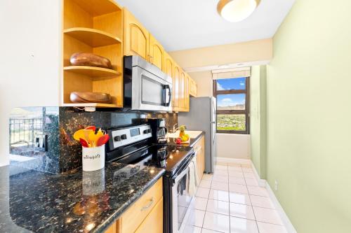 a kitchen with a stove and a microwave at Beautiful Mountain Views & Steps to Waikiki Beach in Honolulu