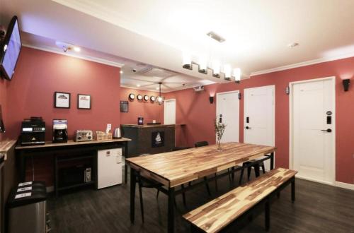 a room with a table and a kitchen with red walls at Blueboat Hostel Jeonju in Jeonju