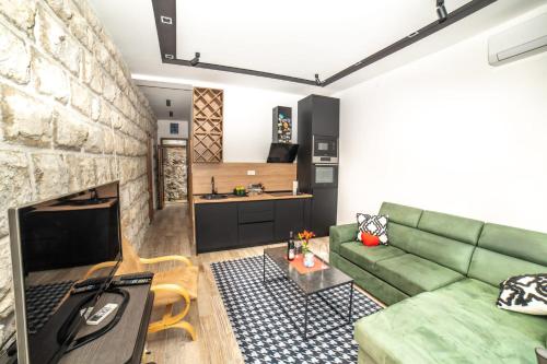 sala de estar con sofá verde y pared de piedra en Apartman Roccia, en Trebinje