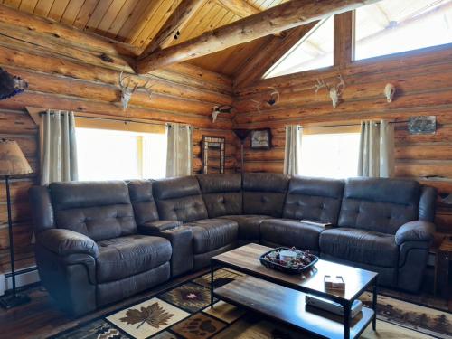 a living room with a leather couch in a cabin at Sportsman Lodge Melrose MT in Melrose