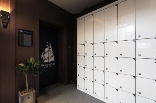 a locker room with white cabinets and a potted plant at Blueboat Hostel Jeonju in Jeonju