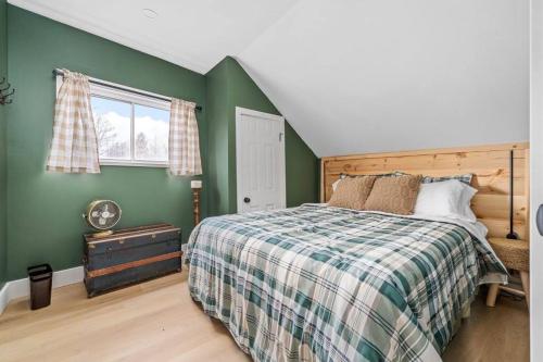 1 dormitorio con cama y pared verde en Urban Cabin - Downtown Picton, en Picton