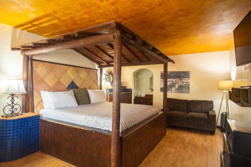 Inn At Avila Beach في أفيلا بيتش: غرفة نوم مع سرير مظلة وأريكة