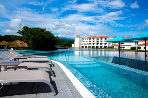 uma piscina com cadeiras e guarda-sóis e um edifício em Ecoland Hotel em Jeju