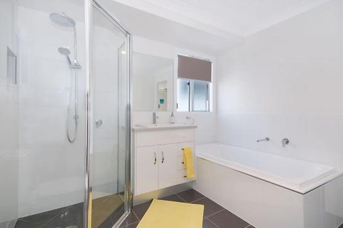 a bathroom with a shower and a sink and a tub at DELUXE Escape! Central, NEW & Spacious 3 Bed in Yamba