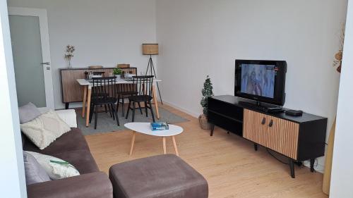 a living room with a couch and a tv at SUNSET APTO in Póvoa de Varzim