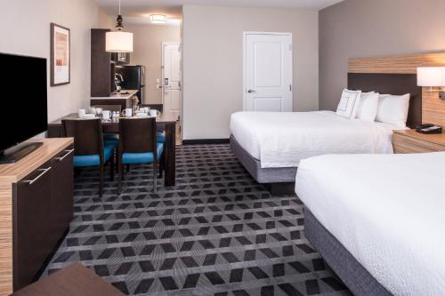 TownePlace Suites by Marriott San Bernardino Loma Linda في لوما ليندا: غرفة فندقية بسريرين وغرفة طعام